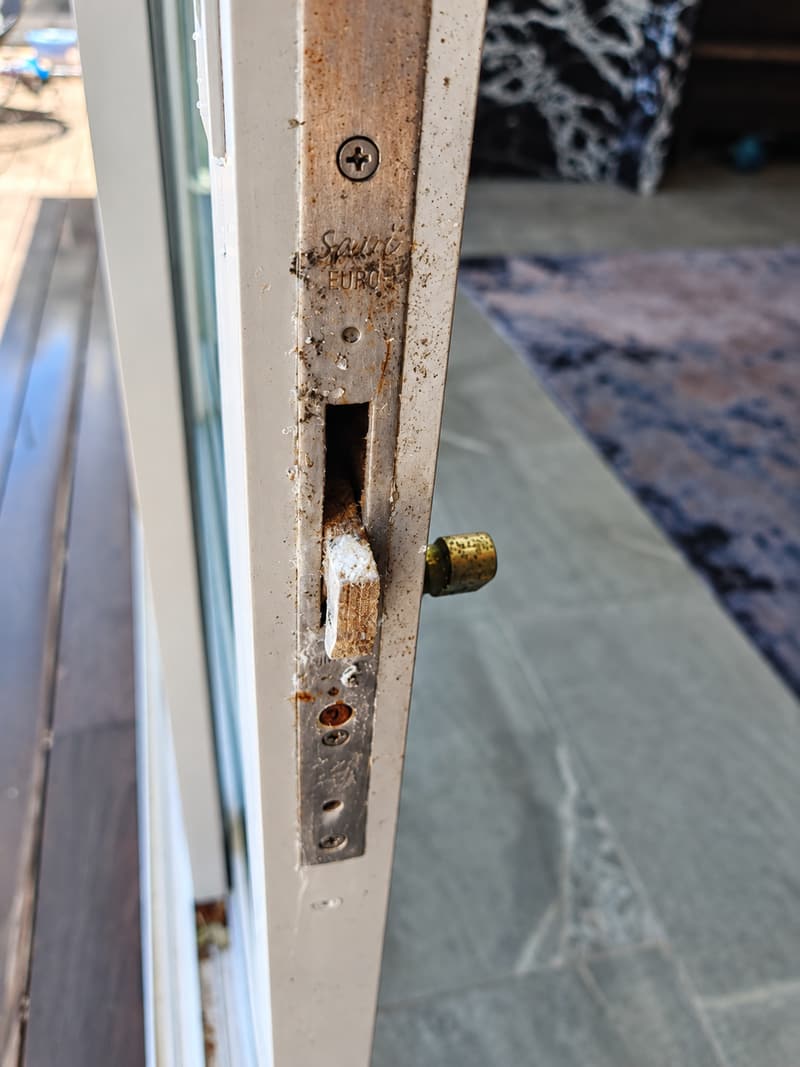 Corroded lock and latch in the edge of a sliding door.