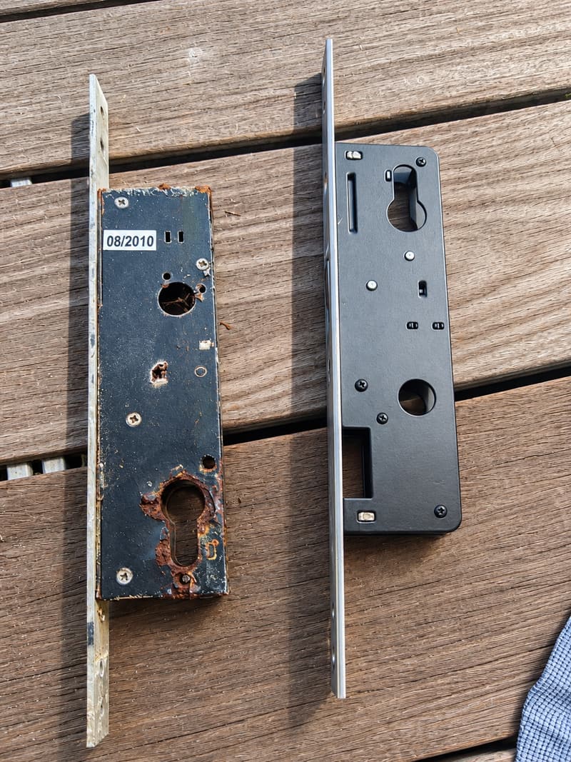 A rusted sliding door lock body beside a new replacement lock body.